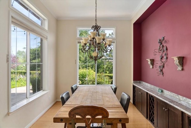 dining space featuring an inviting chandelier, baseboards, crown molding, and light wood finished floors