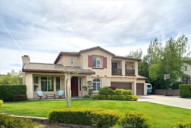 view of front of house featuring driveway, a tile roof, a front yard, a garage, and stucco siding