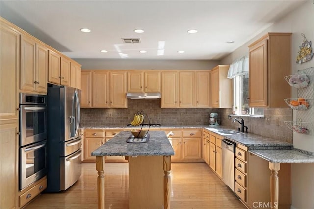 kitchen with under cabinet range hood, stainless steel appliances, and light brown cabinets