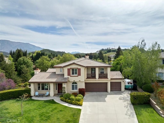 mediterranean / spanish-style home featuring driveway, a chimney, a tile roof, a front lawn, and stucco siding