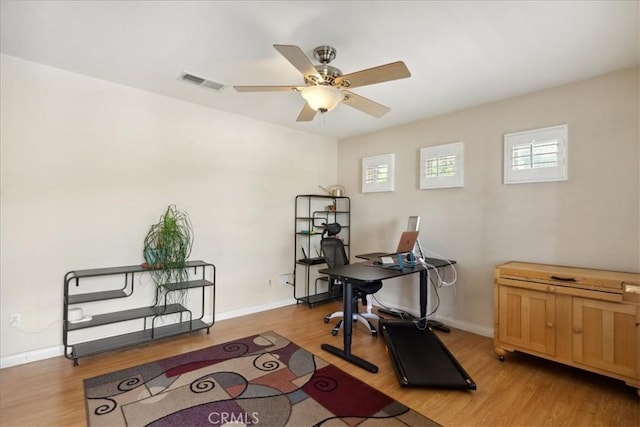 office space featuring a ceiling fan, baseboards, visible vents, and light wood-type flooring