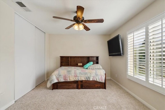 carpeted bedroom featuring a ceiling fan, visible vents, and a closet