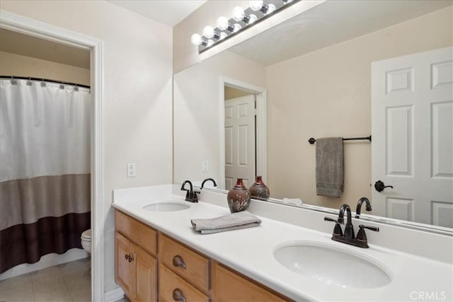bathroom with double vanity, toilet, a sink, and tile patterned floors