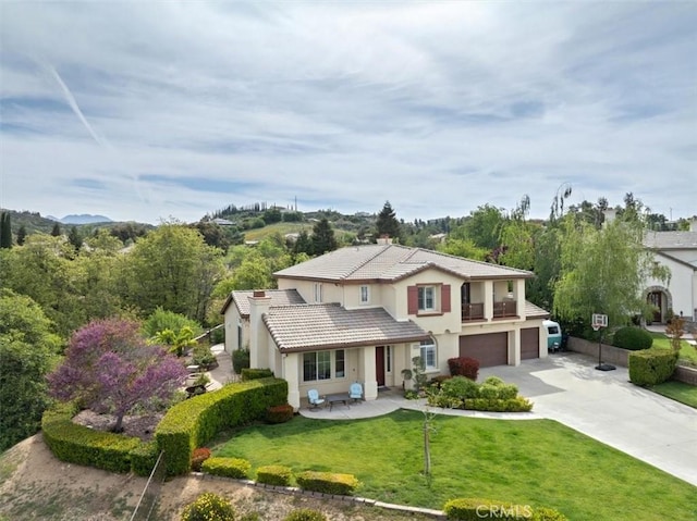 view of front of home with a garage, a balcony, a front yard, concrete driveway, and a tile roof