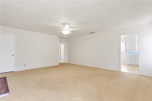 empty room featuring light colored carpet, ceiling fan, and visible vents