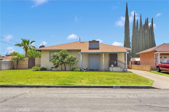 view of front facade featuring stucco siding, fence, solar panels, and a front lawn