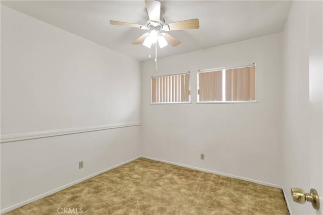 carpeted spare room with baseboards and ceiling fan
