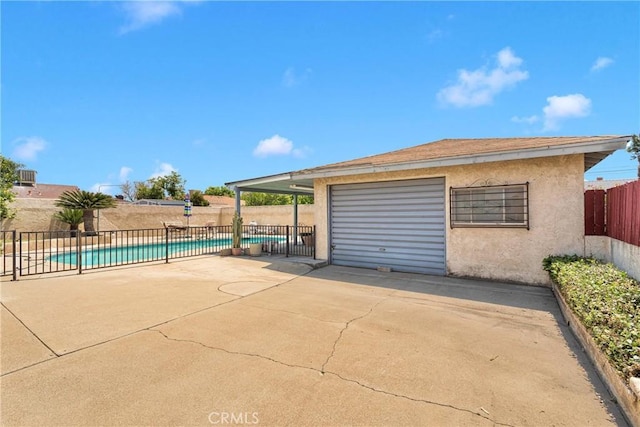 garage featuring a fenced in pool, fence, and concrete driveway