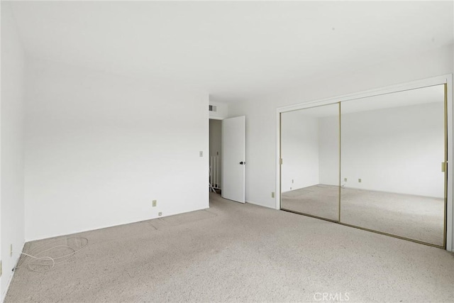unfurnished bedroom with carpet flooring, visible vents, and a closet