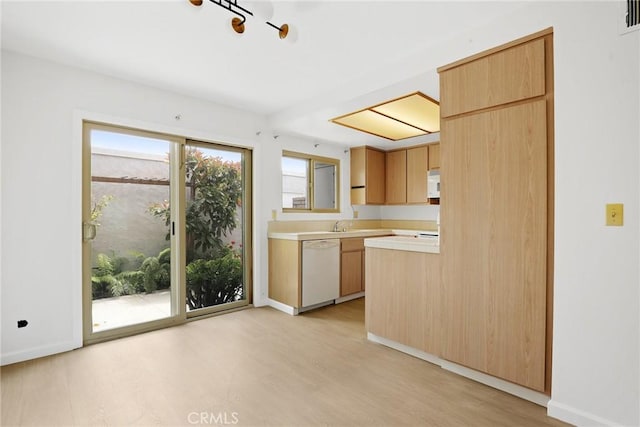 kitchen with light wood finished floors, dishwasher, light countertops, baseboards, and visible vents