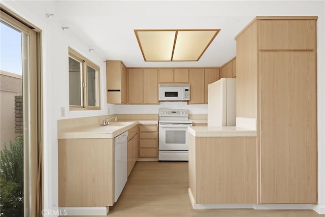 kitchen with light brown cabinets, white appliances, light wood-type flooring, tile countertops, and a sink