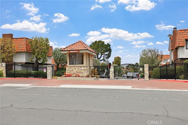 view of road with a gated entry, a gate, and curbs