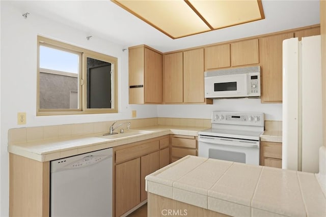 kitchen with white appliances, tile counters, light brown cabinetry, and a sink