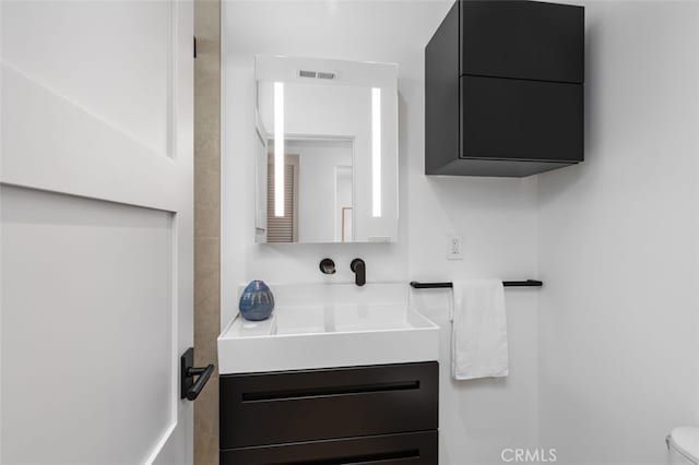 bathroom with vanity, toilet, and visible vents