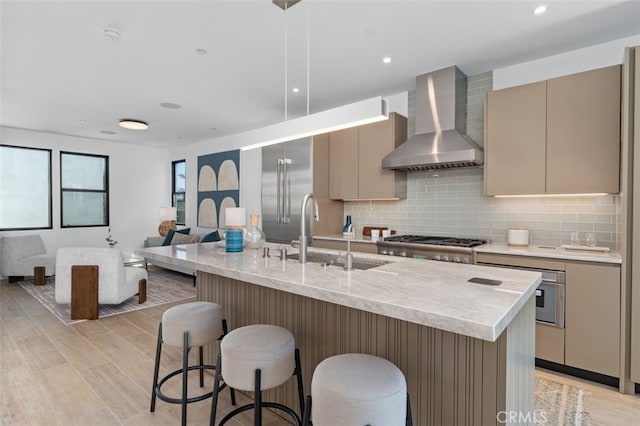 kitchen with gray cabinets, wall chimney exhaust hood, a sink, appliances with stainless steel finishes, and backsplash