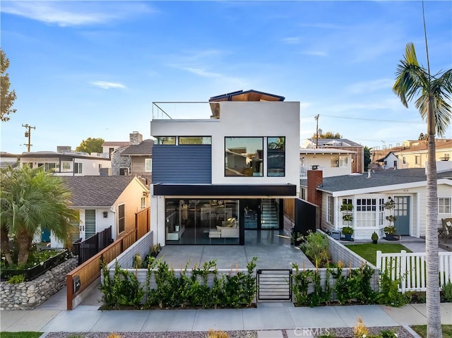 rear view of property with a gate, a fenced front yard, stucco siding, and a residential view