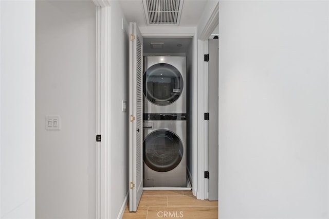 washroom featuring laundry area, visible vents, light wood-type flooring, baseboards, and stacked washer and clothes dryer