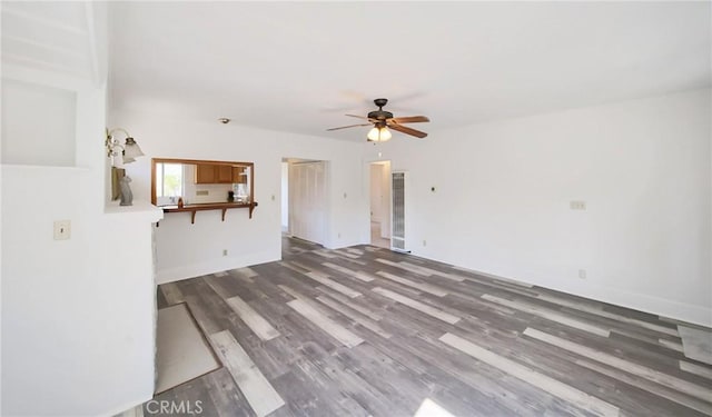 unfurnished living room with a ceiling fan, a heating unit, and wood finished floors