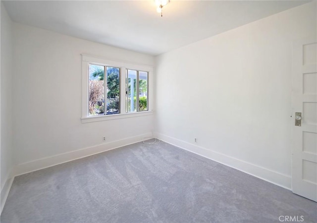 carpeted spare room featuring baseboards