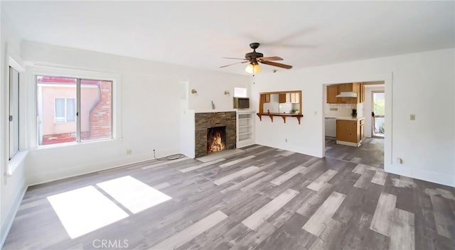 unfurnished living room featuring baseboards, a fireplace, a ceiling fan, and dark wood-style flooring