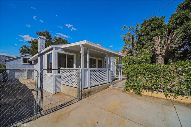 view of front of home featuring fence, a gate, a chimney, and a porch