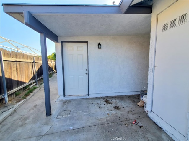 property entrance with stucco siding and fence