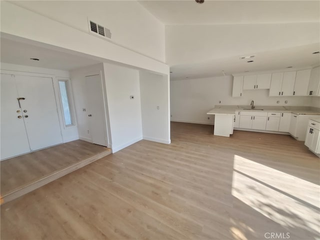 kitchen featuring white cabinets, open floor plan, visible vents, and light wood finished floors
