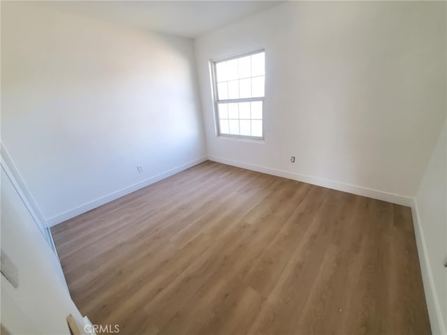 unfurnished room with baseboards and light wood finished floors