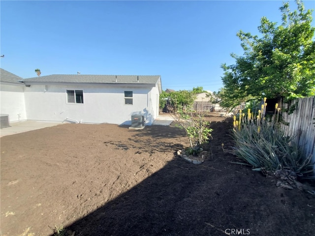 rear view of property with a fenced backyard, stucco siding, central AC, and a patio area