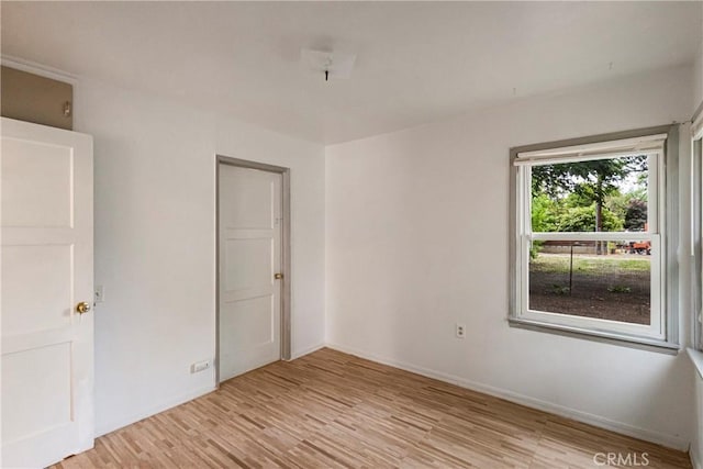 spare room featuring baseboards and light wood-type flooring
