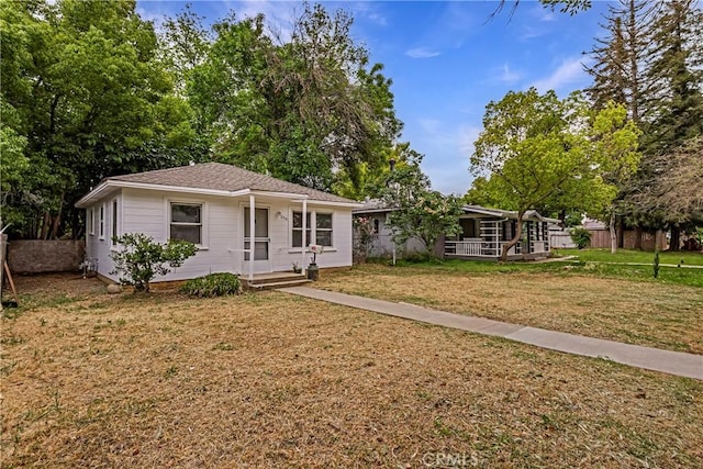ranch-style home featuring covered porch and a front lawn