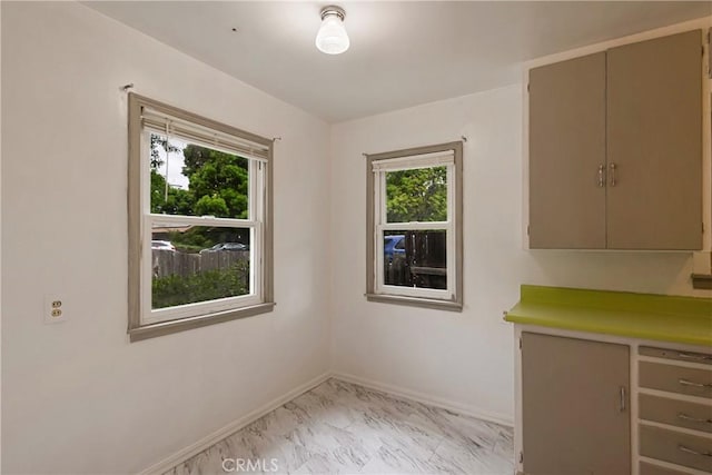 unfurnished dining area featuring baseboards, plenty of natural light, and marble finish floor