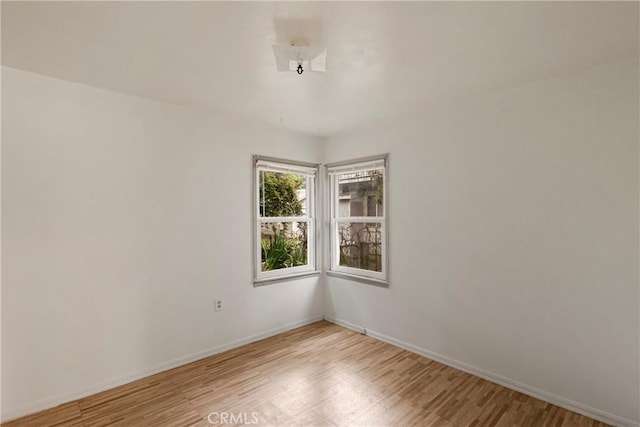 unfurnished room featuring baseboards and light wood-type flooring