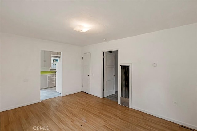 empty room featuring baseboards and light wood finished floors