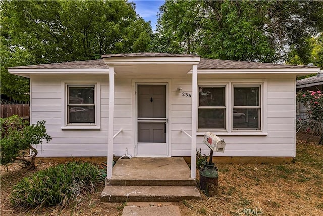 bungalow-style home featuring fence and roof with shingles