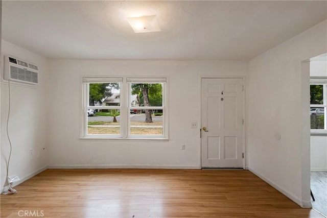interior space featuring a wall mounted AC, plenty of natural light, and light wood-style floors
