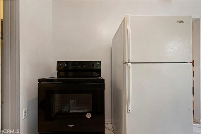 kitchen with black electric range oven and freestanding refrigerator