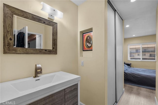 bathroom with wood finished floors, recessed lighting, ensuite bath, and vanity