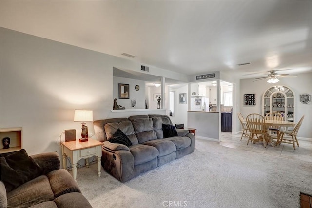 living area with visible vents, ceiling fan, light tile patterned floors, and light carpet