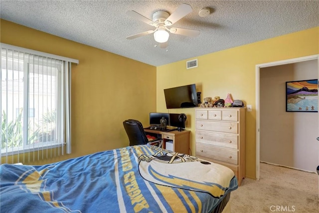 bedroom with a ceiling fan, light colored carpet, a textured ceiling, and visible vents