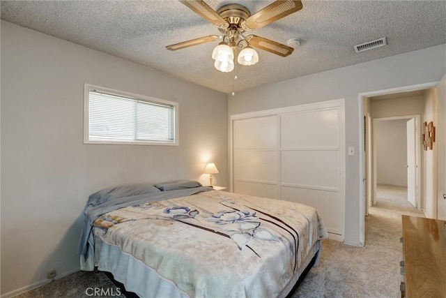 carpeted bedroom with visible vents, a ceiling fan, a textured ceiling, and a closet
