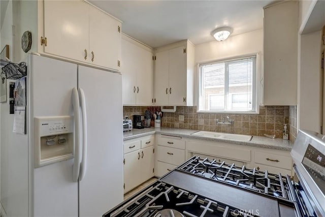 kitchen featuring decorative backsplash, light countertops, white cabinetry, a sink, and white fridge with ice dispenser