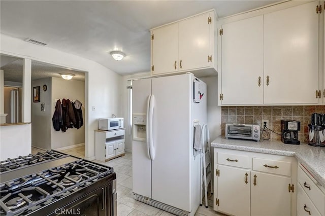 kitchen featuring white appliances, light countertops, a toaster, tasteful backsplash, and visible vents