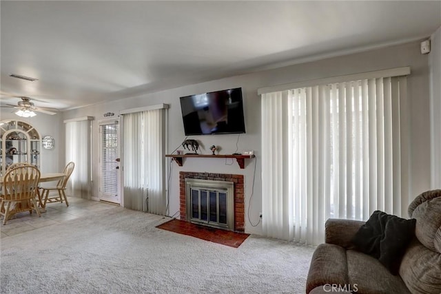 carpeted living area with a ceiling fan and a fireplace