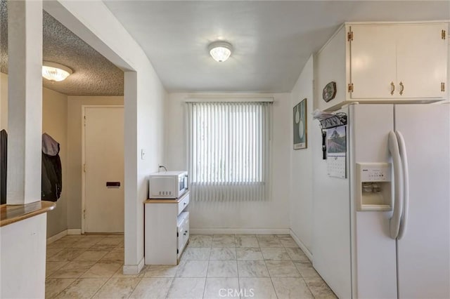 kitchen with baseboards and white appliances