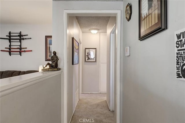 corridor featuring a textured ceiling, light carpet, and baseboards