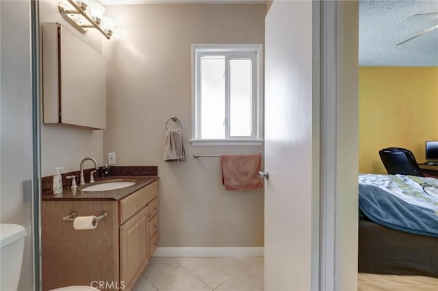ensuite bathroom with connected bathroom, vanity, toilet, tile patterned floors, and baseboards