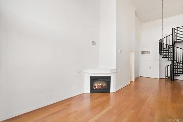1465 C St Unit 3604, San Diego, CA 92101 - unfurnished living room with a towering ceiling, stairway, light wood finished floors, and a glass covered fireplace