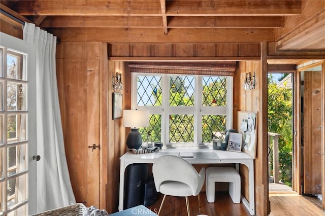 dining room with wood walls, wood finished floors, a wealth of natural light, and beamed ceiling