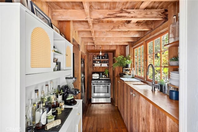 kitchen featuring dark wood-style flooring, a sink, gas range, beamed ceiling, and wood ceiling